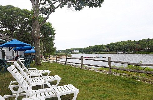 Three white lounging chairs by a fence overlooking a large river