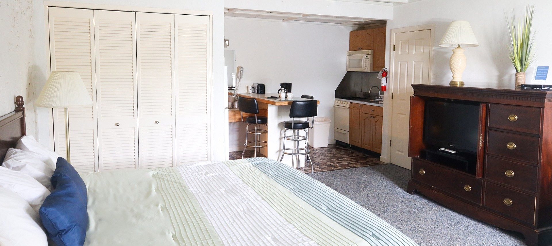 Bedroom with queen bed, kitchenette, closet, and wood hutch with a TV