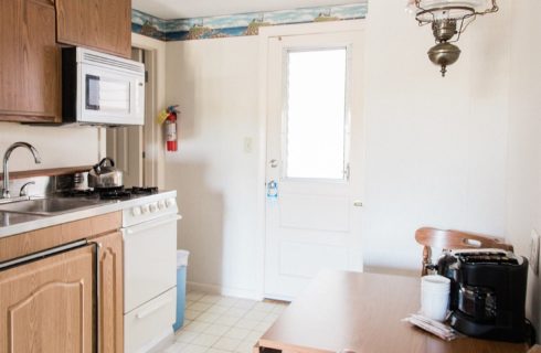 Small kitchen area with sink, stove, microwave and table for two