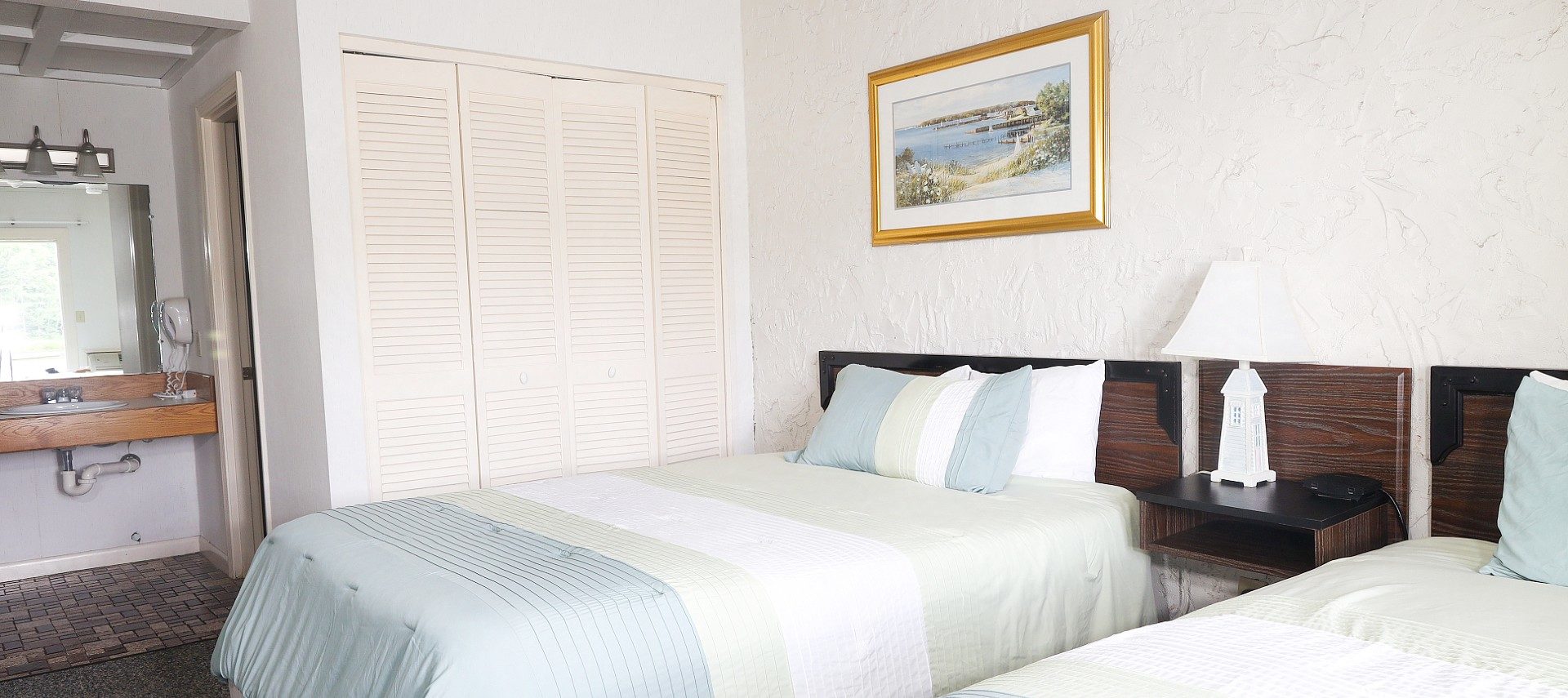 Bedroom with two queen beds with wood headboards and in-room sink with mirror