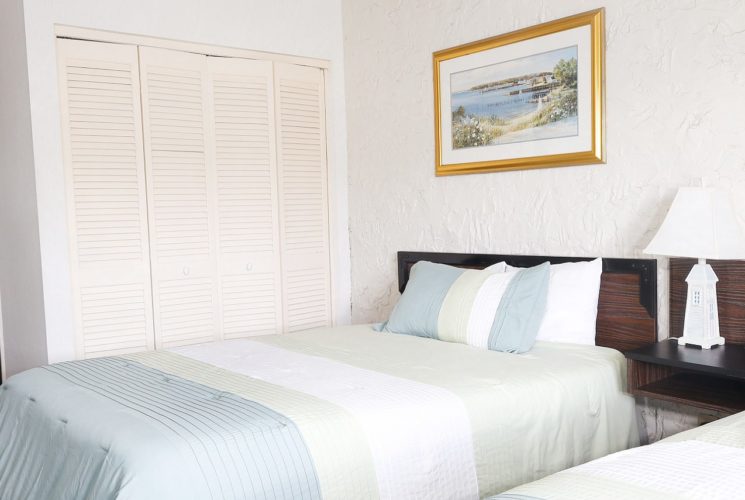 Bedroom with two queen beds with wood headboards and in-room sink with mirror