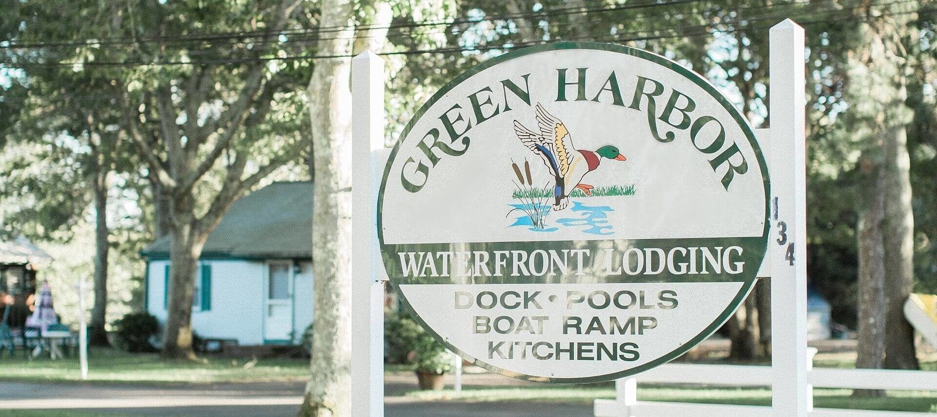 White oval business sign with green text and picture of a duck over water